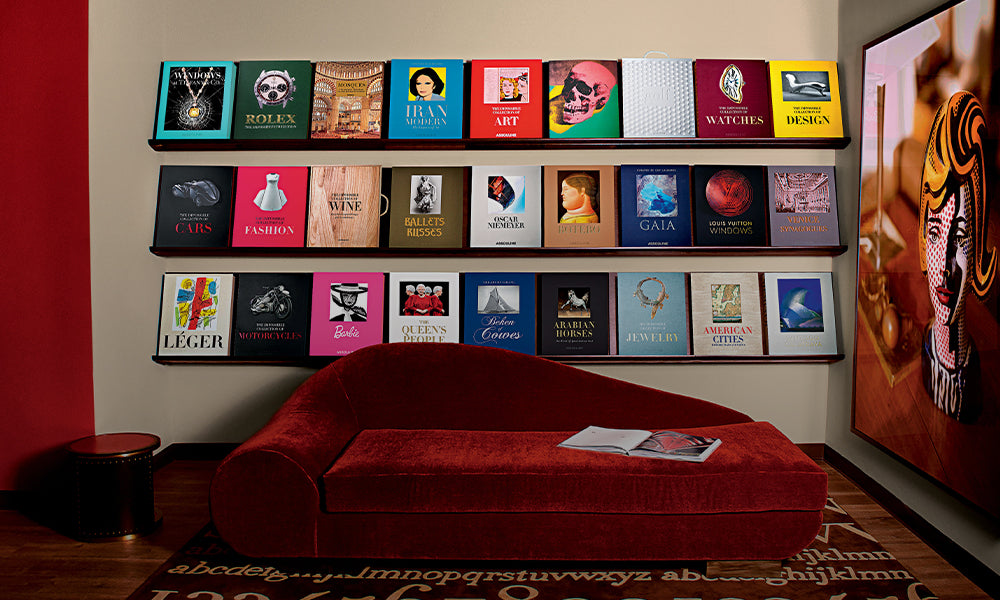 Office space with a red couch and multiple coffee table books placed as decorations on the wall