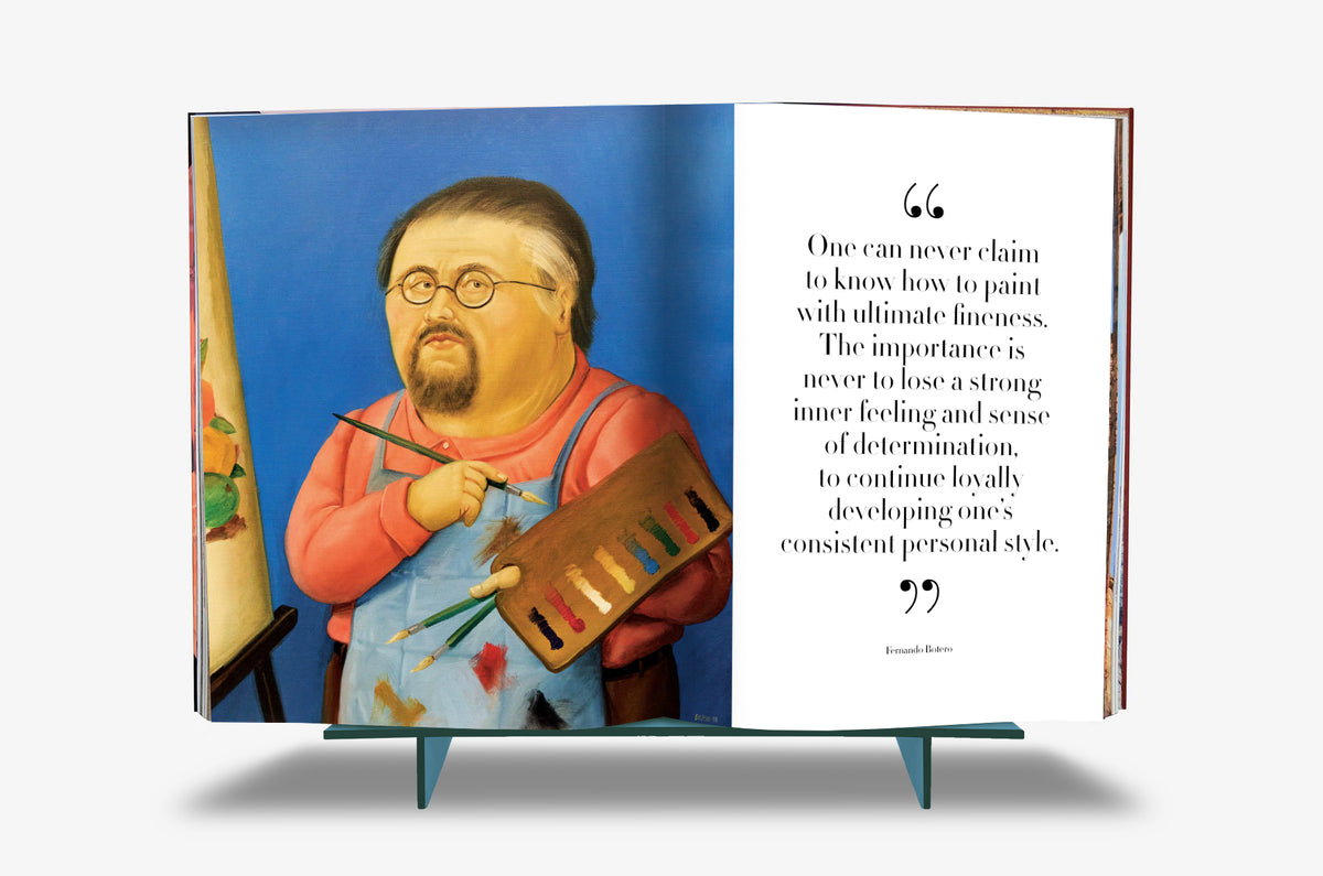 Fernando Botero XXL by Assouline: Book open to a self-portrait spread — Botero depicted as a rotund painter in a blue smock and pink sweater, round glasses and a goatee, holding brushes and a paint-daubed palette before a vivid blue background; the facing page carries his quote: "One can never claim to know how to paint with ultimate fineness. The importance is never to lose a strong inner feeling and sense of determination, to continue loyally developing one's consistent personal style."