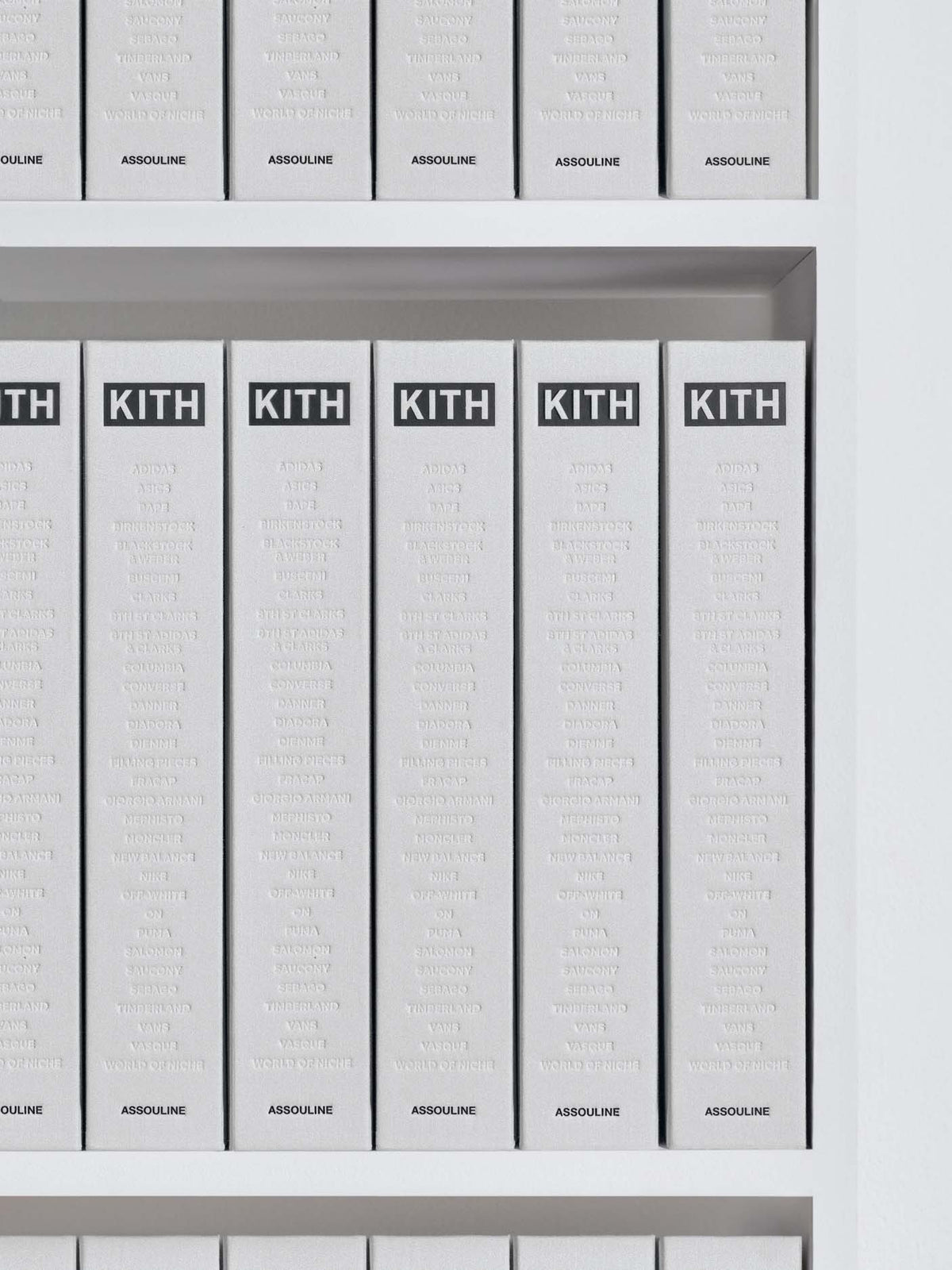 A close-up of a row of white Kith Absolue booklets or slim boxes standing upright on a shelf, with the KITH logo printed in black at the top of each item.