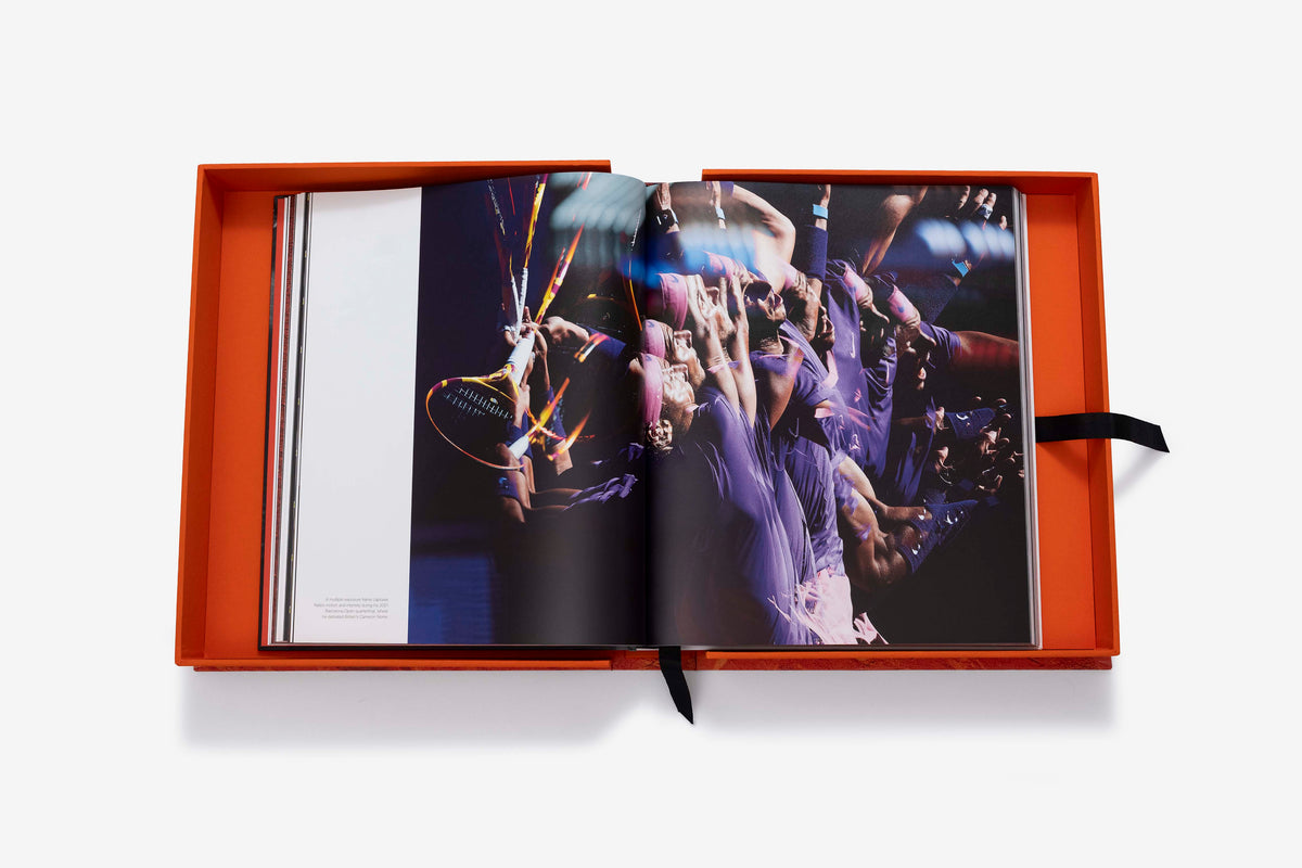 Rafa Nadal (Ultimate) by Assouline: the companion book open inside its orange presentation case to a stroboscopic multiple-exposure photograph of a player serving in purple attire