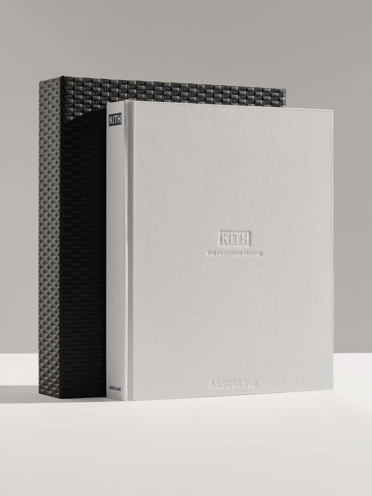 A Kith Assouline book standing upright next to its textured black woven-patterned slipcase, photographed on a clean light gray studio background.